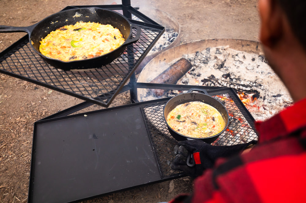 Campfire cooking grill combo with mesh grill racks and solid hotplate surface designed for campfire cooking, outdoor grilling and campsite meal preparation