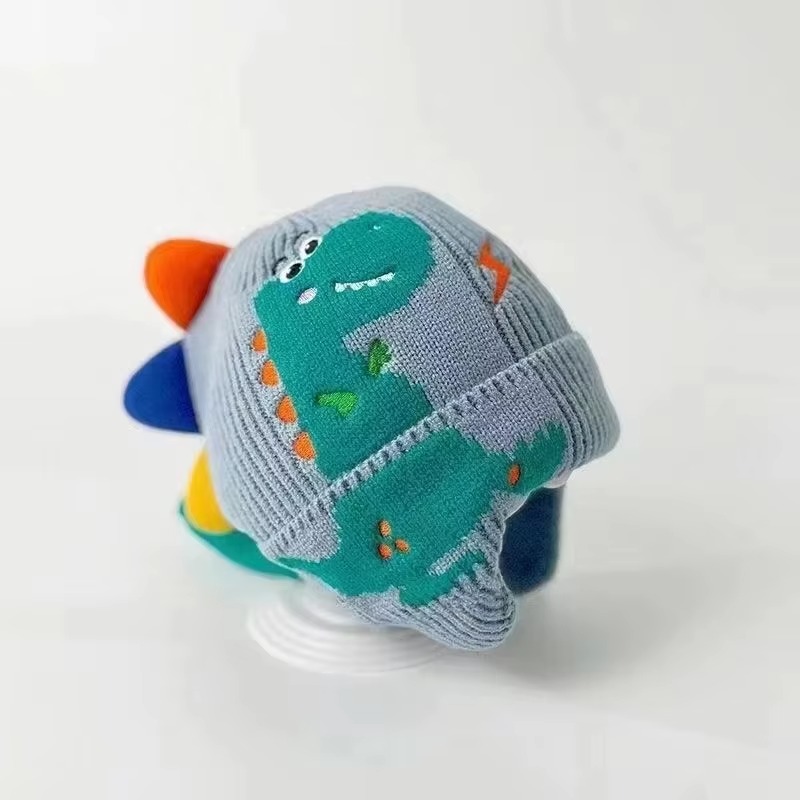 Adorable knitted kids winter beanie featuring a playful 3D dinosaur design with colorful spikes, ear flaps, and a soft ribbed cuff. Made from warm, comfortable knit fabric, this toddler and children's hat provides excellent cold-weather protection for the