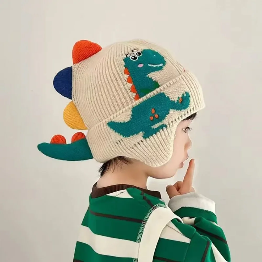 3D Dinosaur Kids Winter Beanie with Ear Protection Adorable knitted kids winter beanie featuring a playful 3D dinosaur design with colorful spikes, ear flaps, and a soft ribbed cuff. Made from warm, comfortable knit fabric, this toddler and children's hat provides excellent cold-weather protection for the