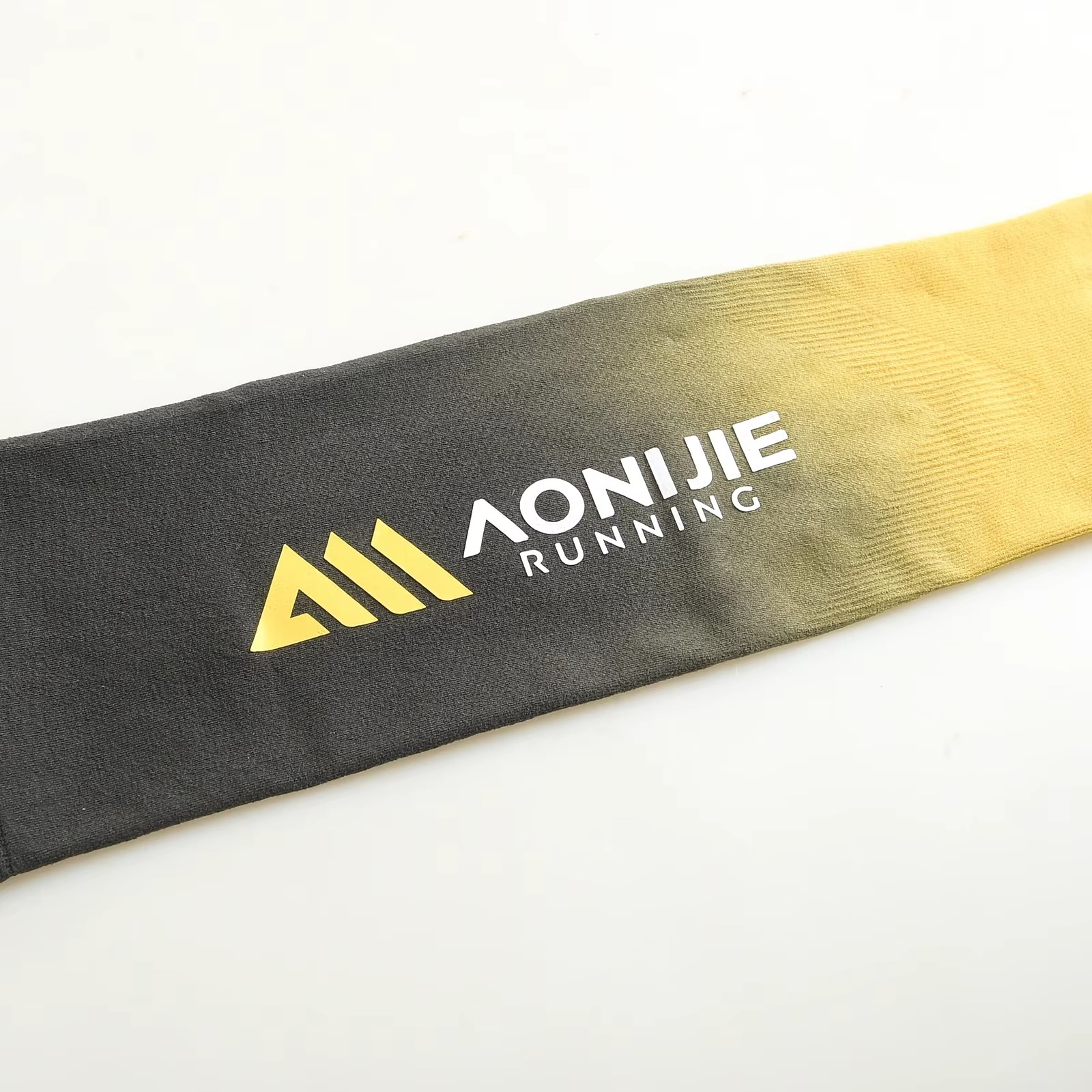 Side view of AONIJIE gradient running arm sleeve in black to yellow worn by athlete with sleeveless top