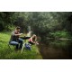 Couple cooking outdoors beside a river using a Dometic CADAC Skottel Braai portable camping barbecue