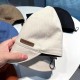 Close-up of a white summer bucket hat with a "Hand Made" label and rear adjustable toggle, held by hand.
