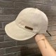 A beige women’s bucket hat with a "Hand Made" label on the side, shown against a brick wall background.