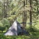 Pomoly HUSSAR 20 Tent in Forest Setup Pomoly HUSSAR 20 hot tent set up in a dense forest with a stove pipe installed and the front awning extended.