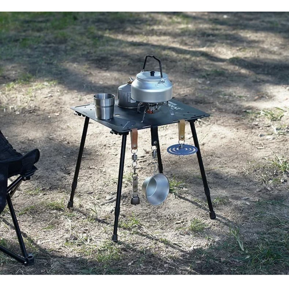 Single table used outdoors with cookware and hanging utensils on gravel surface.