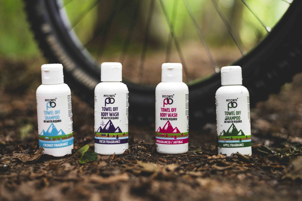 Four Pits & Bits hygiene bottles displayed upright, including body wash and shampoo in various fragrances.