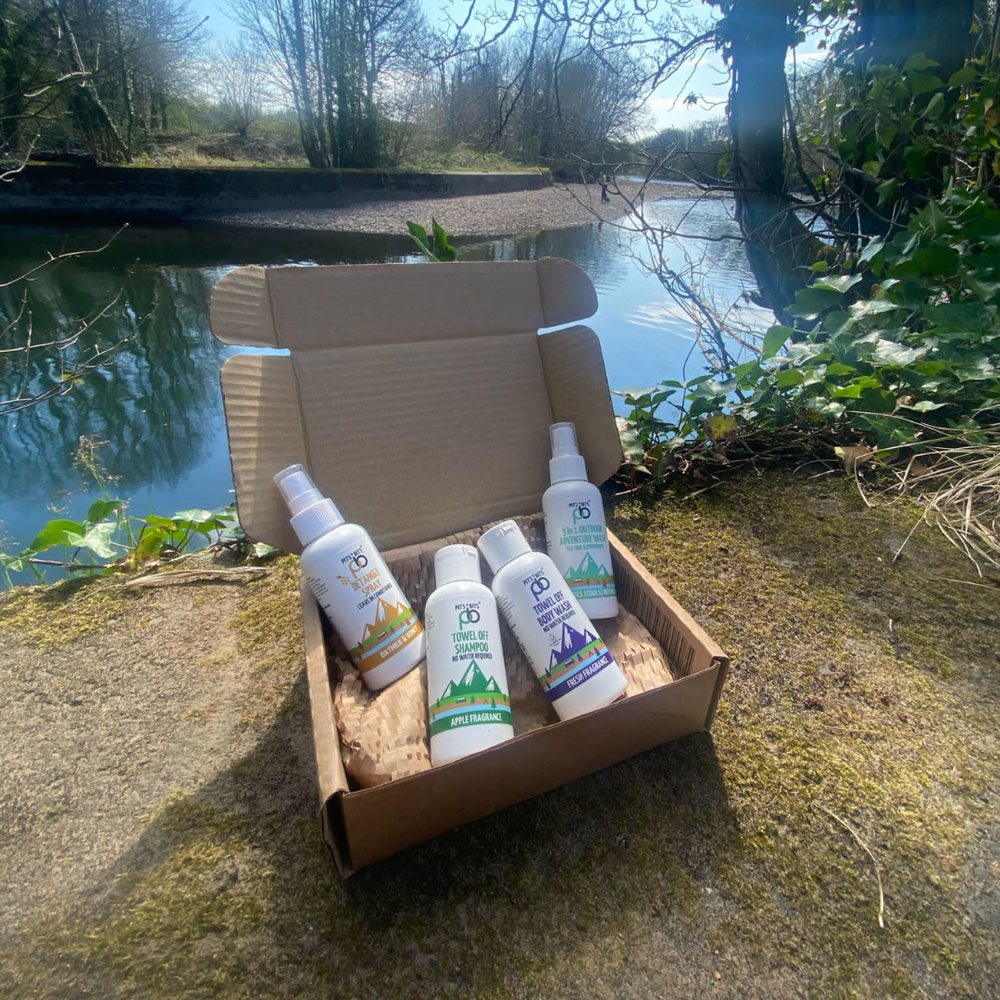 Open Pits & Bits travel wash kit on a stone surface beside a river, with natural background