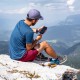 Charging a Phone with Xtorm Power Bank on a Mountain Man charging his phone with Xtorm rugged power bank while sitting on a rocky mountain cliff.