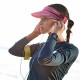 Female runner wearing wine red AONIJIE sports visor cap with pink strap while adjusting earphones.