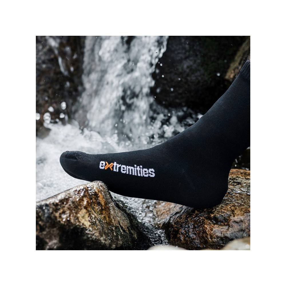 Close-up of a foot wearing Extremities waterproof sock standing in a flowing stream, emphasizing waterproof capability.