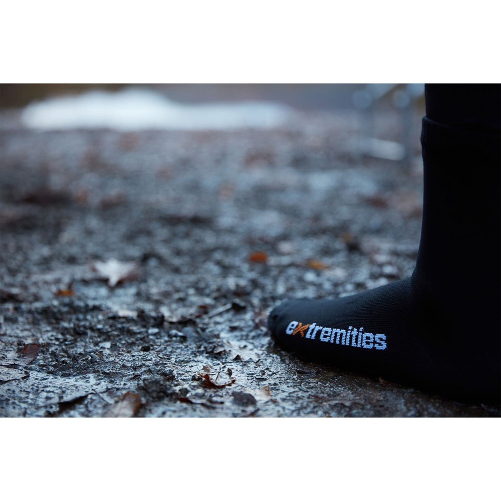 Foot wearing Extremities Evolution waterproof sock stepping on wet, muddy ground with fallen leaves.