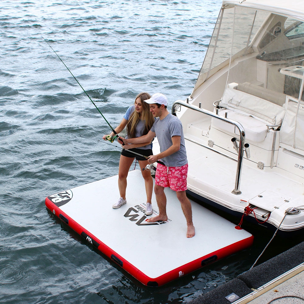 People fishing from Aqua Marina inflatable air platform attached beside luxury yacht on open water ideal for relaxing swimming and marine recreation